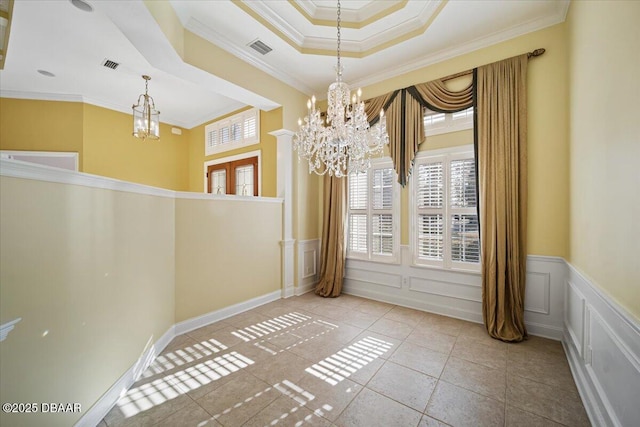 tiled empty room with crown molding, a chandelier, and a raised ceiling