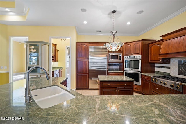 kitchen featuring sink, tasteful backsplash, built in appliances, a kitchen island, and pendant lighting