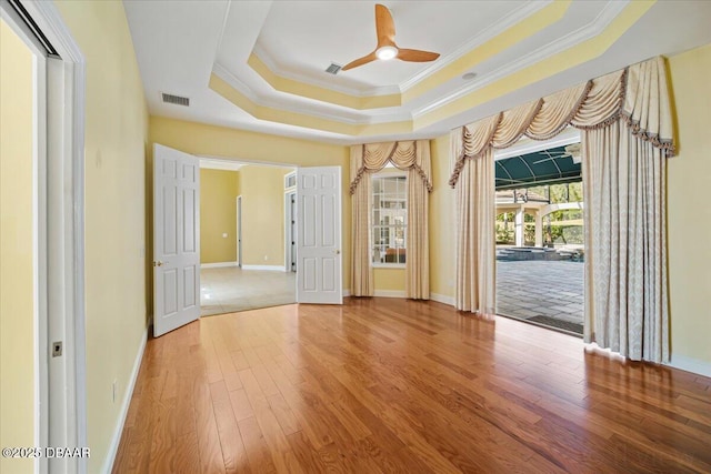 spare room with crown molding, hardwood / wood-style floors, a tray ceiling, and ceiling fan