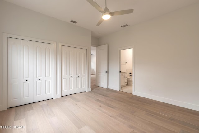 unfurnished bedroom with ceiling fan, ensuite bath, light hardwood / wood-style floors, and two closets