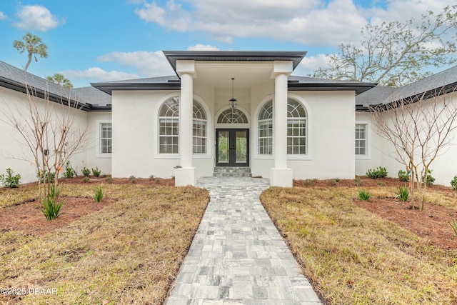 view of exterior entry featuring french doors and a lawn