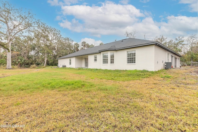 rear view of property with central AC and a lawn