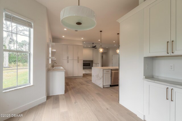 kitchen with dishwasher, sink, pendant lighting, and white cabinets