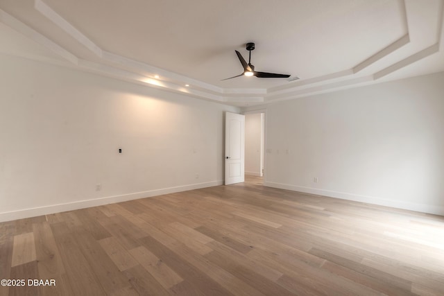 spare room featuring ceiling fan, a raised ceiling, and light wood-type flooring