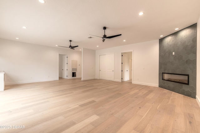 unfurnished living room with ceiling fan, a fireplace, and light hardwood / wood-style floors