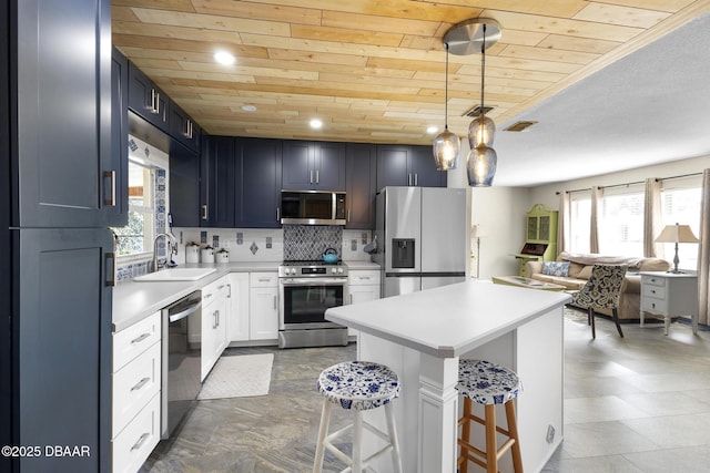 kitchen featuring a sink, a kitchen breakfast bar, light countertops, appliances with stainless steel finishes, and decorative light fixtures