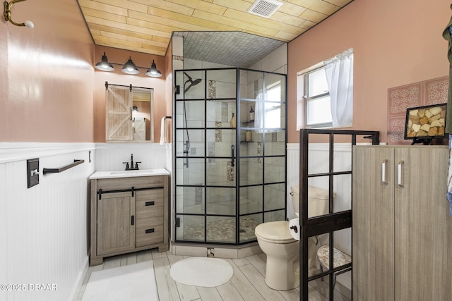 full bath featuring a stall shower, visible vents, toilet, a wainscoted wall, and vanity