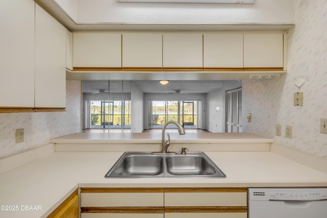 464 Bouchelle Dr Unit 104, New Smyrna Beach, FL 32169 - kitchen with wallpapered walls, light countertops, a sink, white dishwasher, and cream cabinets