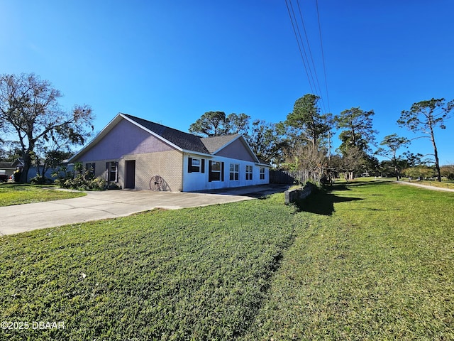 view of front facade with brick siding, driveway, and a front lawn