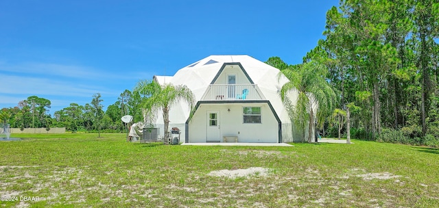 rear view of property featuring a balcony and a lawn