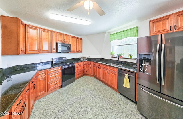 kitchen featuring a textured ceiling, sink, dark stone countertops, and stainless steel appliances