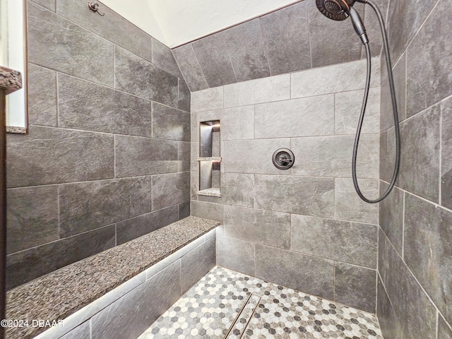 bathroom featuring vaulted ceiling and tiled shower