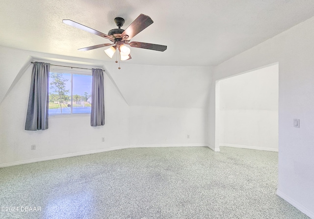 bonus room with lofted ceiling, a textured ceiling, carpet flooring, and ceiling fan