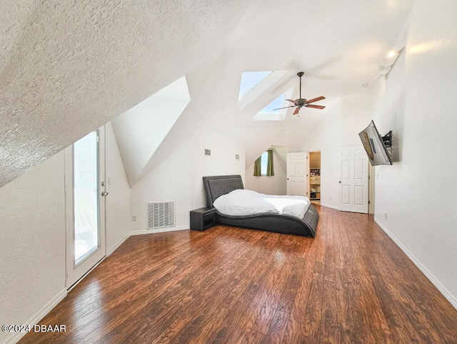 bedroom featuring dark wood-type flooring, access to exterior, a textured ceiling, ceiling fan, and vaulted ceiling with skylight