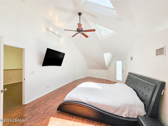 bedroom with hardwood / wood-style floors, vaulted ceiling with skylight, and ceiling fan