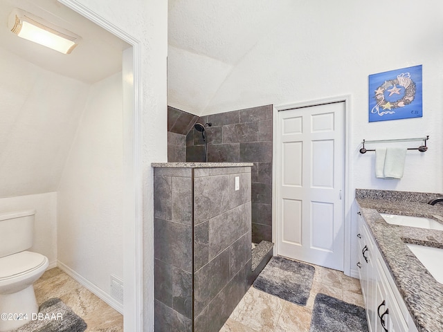 bathroom with toilet, vanity, lofted ceiling, and a tile shower