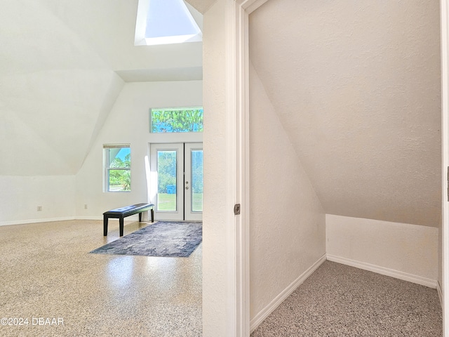 bonus room featuring french doors, a textured ceiling, and vaulted ceiling with skylight