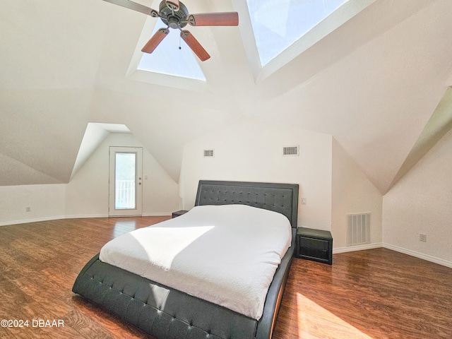 bedroom featuring ceiling fan, vaulted ceiling with skylight, and dark hardwood / wood-style floors