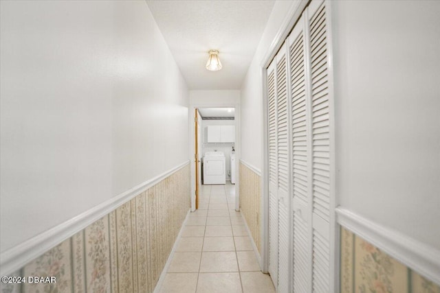 hall with washer / clothes dryer, light tile patterned floors, and a textured ceiling