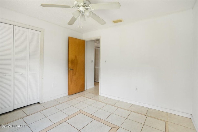 unfurnished bedroom featuring light tile patterned flooring, ceiling fan, and a closet