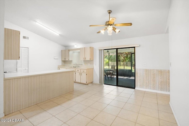 kitchen featuring vaulted ceiling, light brown cabinetry, sink, light tile patterned floors, and ceiling fan