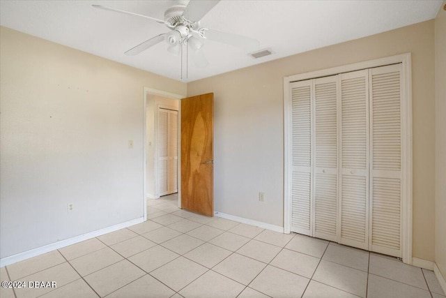 unfurnished bedroom with light tile patterned floors, ceiling fan, and a closet