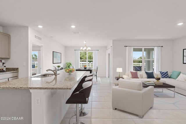 living room featuring sink, a notable chandelier, and light tile patterned flooring