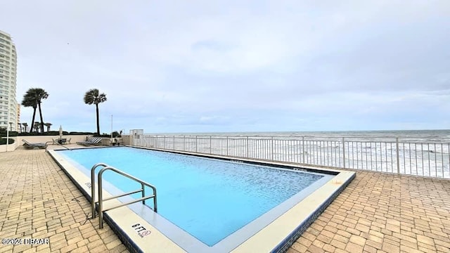 view of pool featuring a water view and a patio area