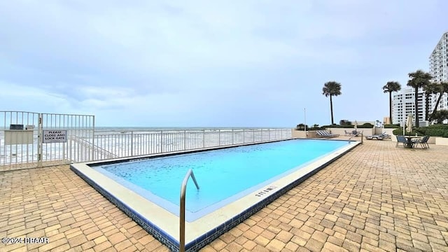 view of swimming pool with a water view and a patio area