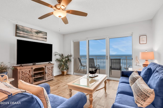 living room featuring a textured ceiling, light hardwood / wood-style floors, and ceiling fan