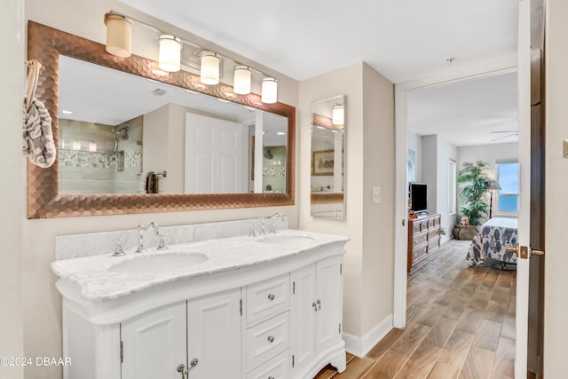 bathroom with ceiling fan, wood-type flooring, vanity, and tiled shower