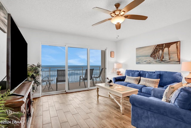 living room featuring a textured ceiling, light hardwood / wood-style floors, and ceiling fan