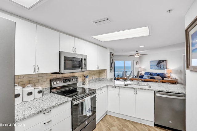 kitchen featuring light hardwood / wood-style floors, stainless steel appliances, white cabinets, sink, and light stone countertops