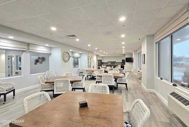 dining space with light hardwood / wood-style floors and a paneled ceiling