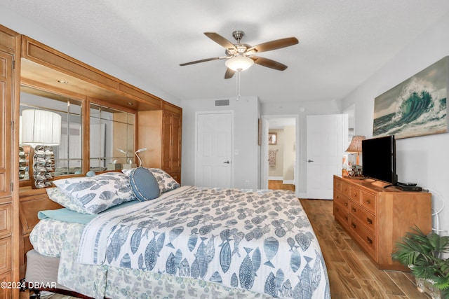 bedroom featuring ceiling fan, a textured ceiling, and dark hardwood / wood-style flooring