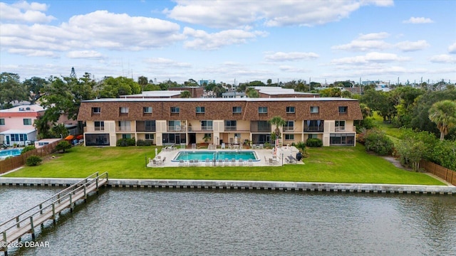 back of property featuring a yard, a water view, and a fenced in pool