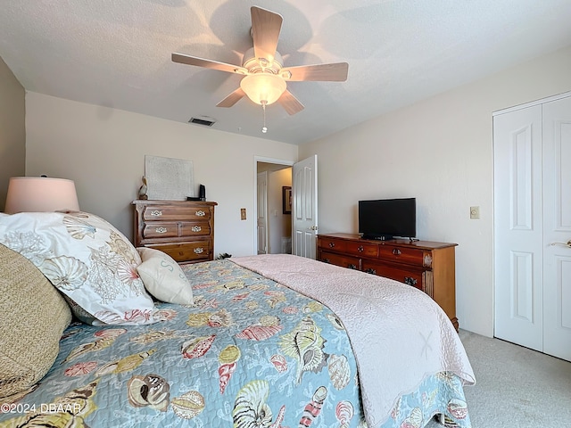 bedroom featuring a ceiling fan, visible vents, light carpet, and a textured ceiling