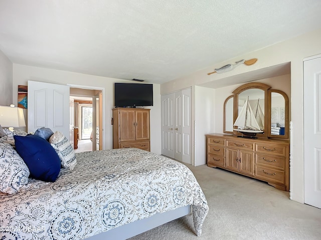 bedroom featuring light carpet, a closet, and a textured ceiling