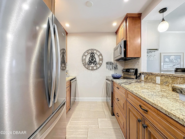 kitchen with stainless steel appliances, light stone counters, brown cabinetry, and baseboards