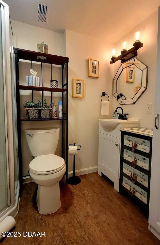 bathroom featuring vanity, toilet, and a shower with shower door