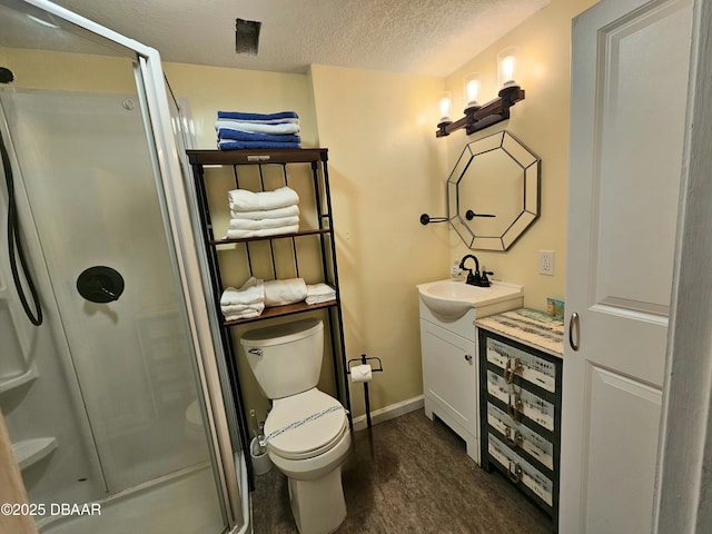 bathroom with a stall shower, vanity, a textured ceiling, and toilet
