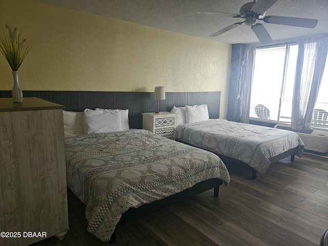 bedroom with a textured ceiling, a textured wall, a ceiling fan, and wood finished floors