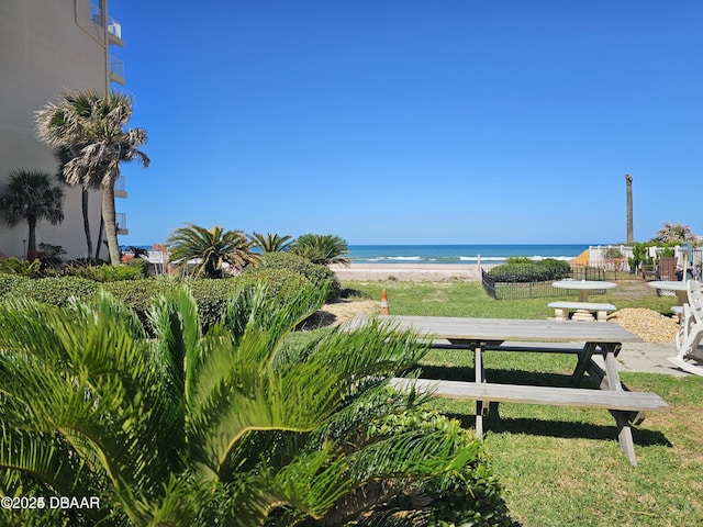 surrounding community with a lawn, a water view, and a view of the beach