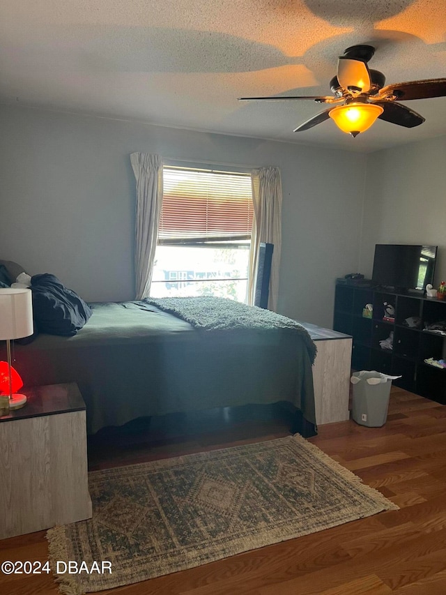 bedroom with a textured ceiling, hardwood / wood-style floors, and ceiling fan