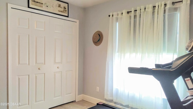 bedroom with baseboards, light wood finished floors, and a closet