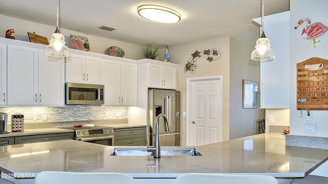 kitchen with stainless steel appliances, tasteful backsplash, pendant lighting, white cabinetry, and a textured ceiling