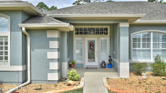 entrance to property with stucco siding and a shingled roof