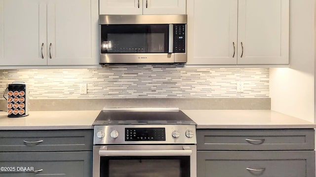 kitchen featuring appliances with stainless steel finishes, gray cabinetry, light countertops, and backsplash