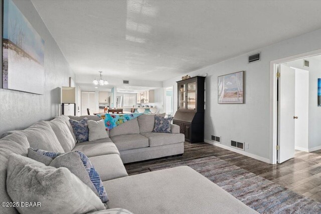 living room with a notable chandelier, wood finished floors, and visible vents