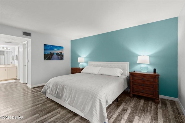 bedroom with visible vents, wood finished floors, and baseboards